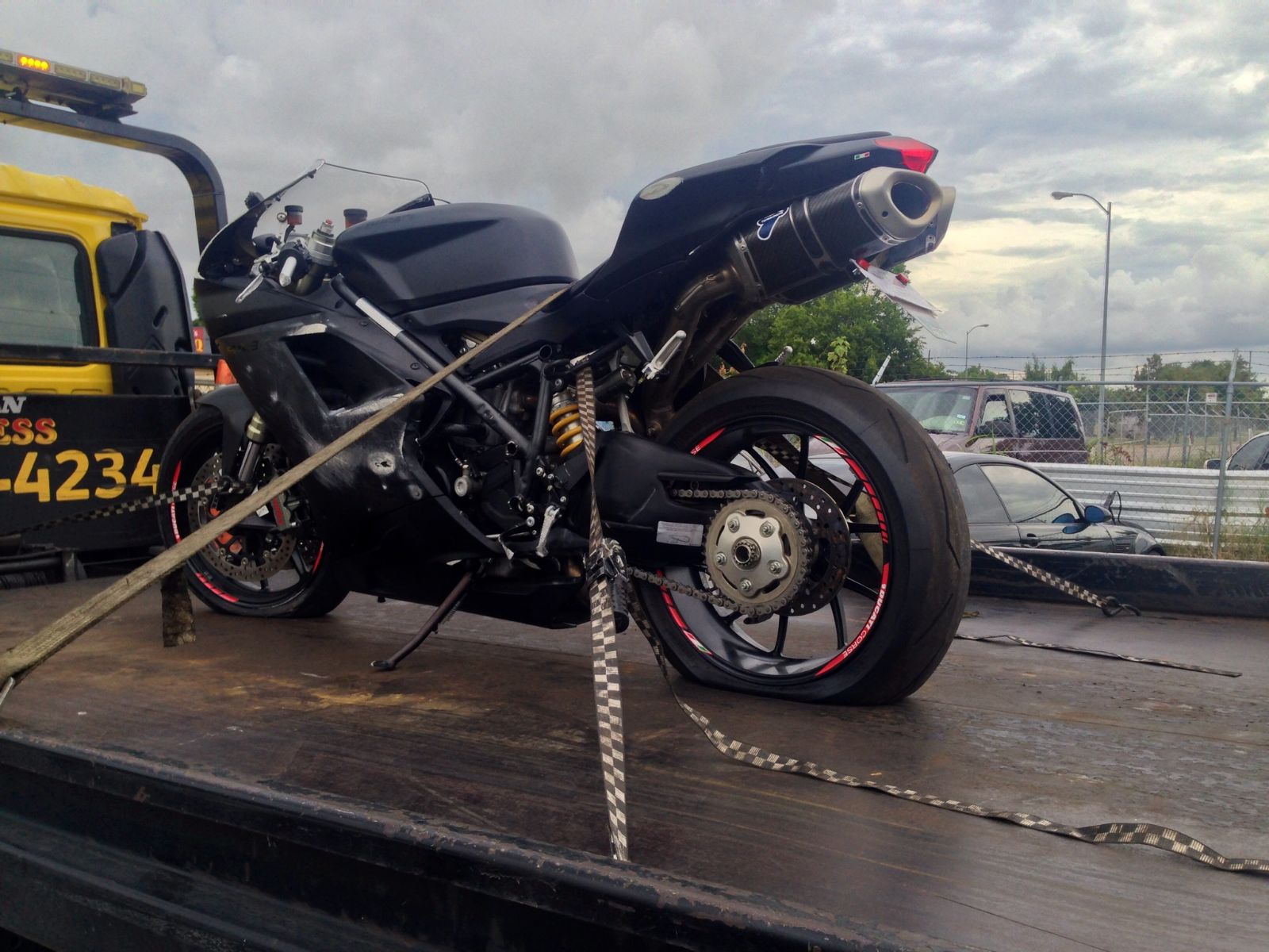 A customer's black Ducati superbike strapped down on a tow-truck flatbed, on its way in for repair