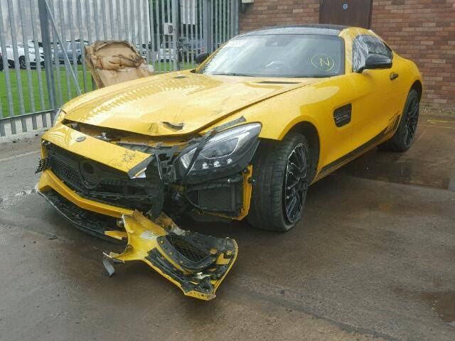 Yellow Mercedes-AMG GT with heavy front-end collision damage, front bumper torn off and hanging on the ground, grille and headlight area crushed