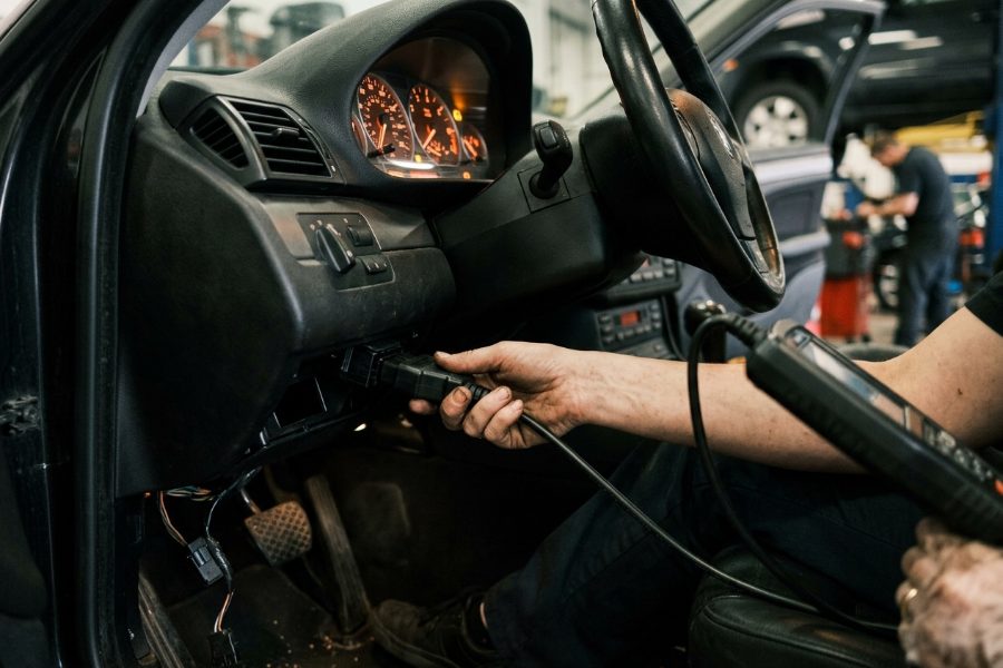 Technician plugging a diagnostic scan tool into a car to read ABS and brake warning codes