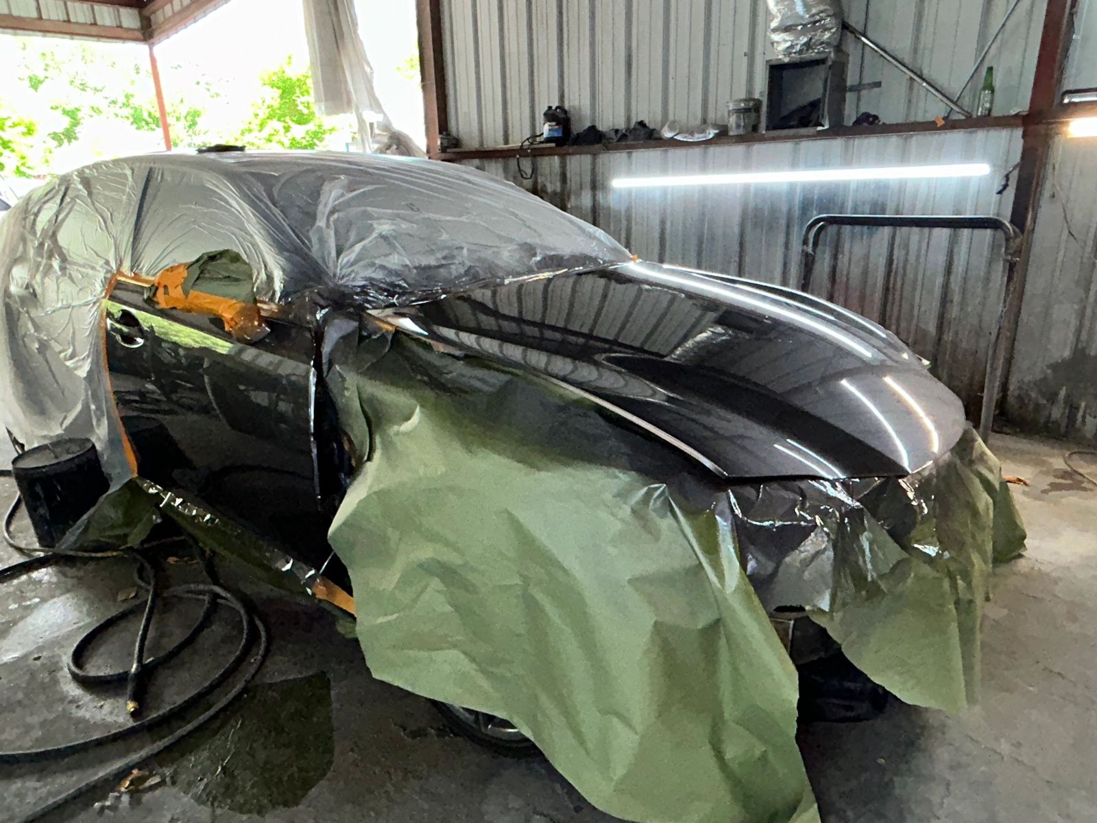 Car undergoing paint job with protective coverings at Astro Collision Houston